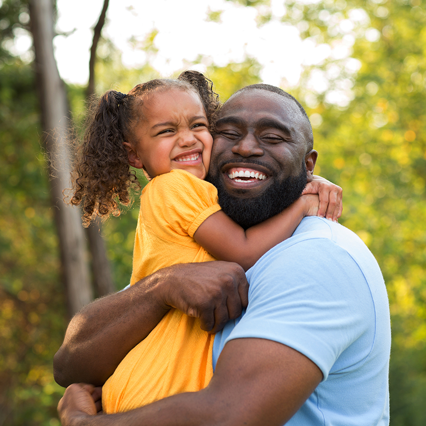 Father holding young daughter smiling