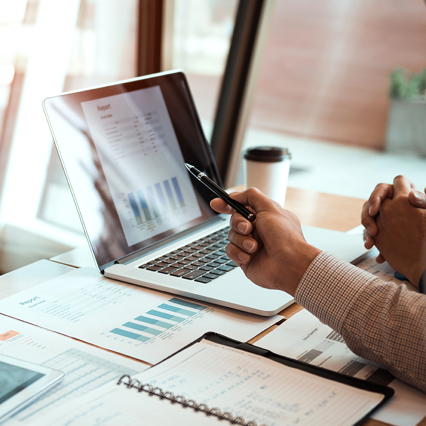 hand pointing at financial report on laptop